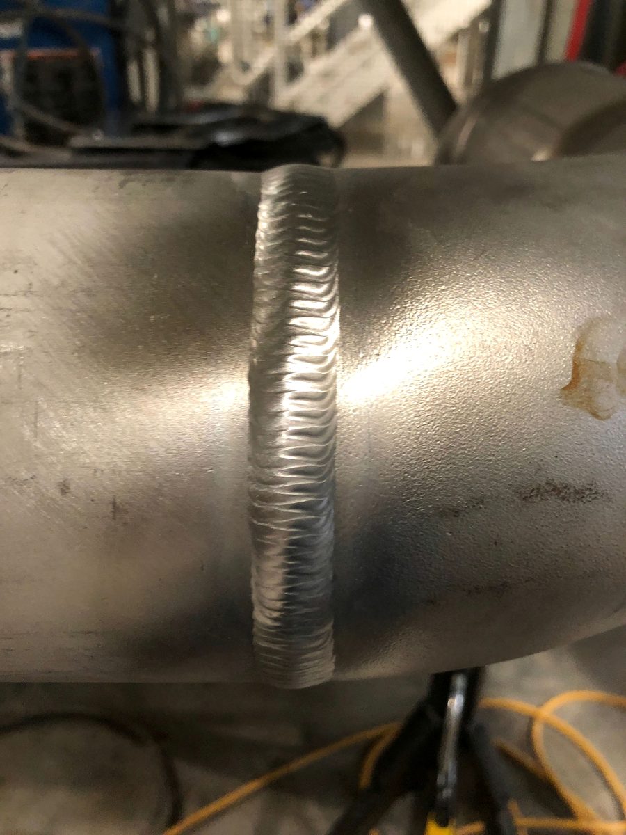 Close-up of a uniform stainless steel TIG weld bead running across a pipe